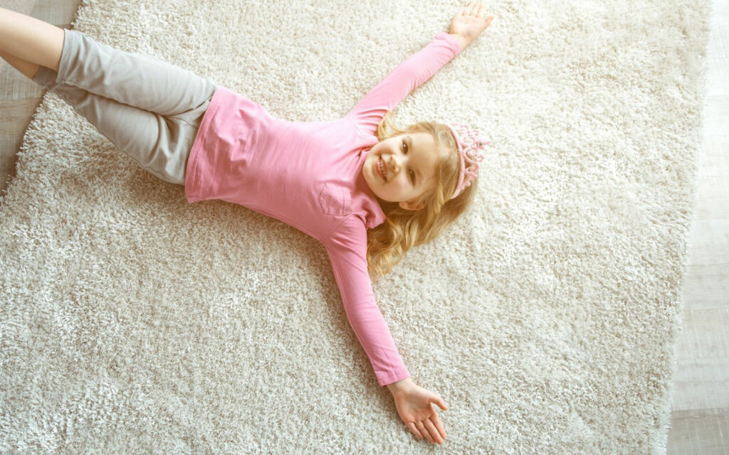 Cute smiling girl laying on rug | Joseph's Flooring